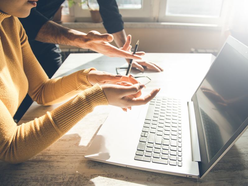 Business owner and colleague reviewing work on a laptop
