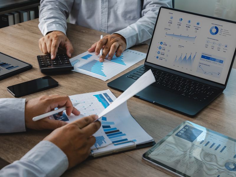 Reviewing financial reports and charts on a laptop and tablet